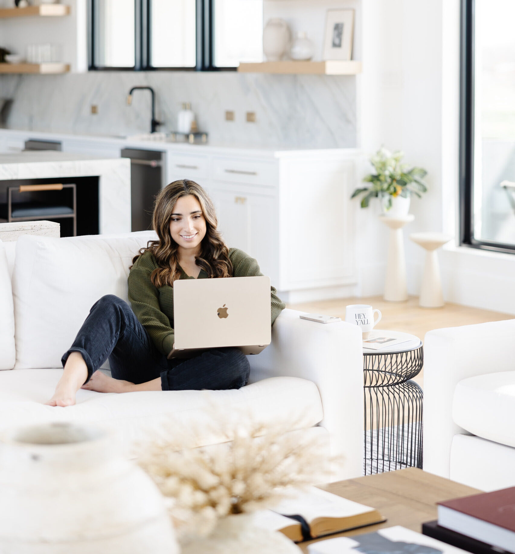 Woman sitting on a couch in a modern house with a laptop